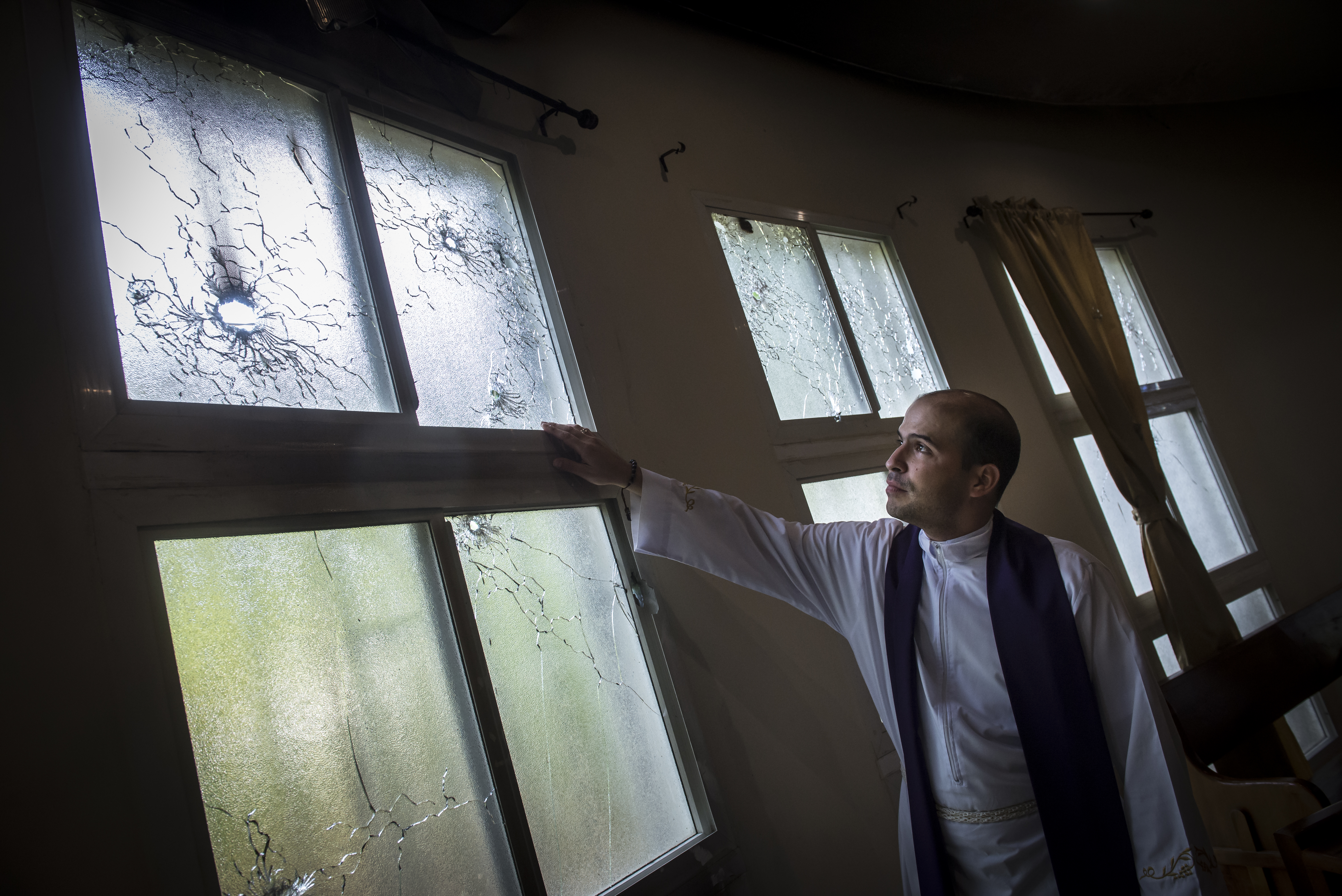 El padre Erick Alvarado, vicario de la parroquia Jesús de la Divina Misericordia, muestra los destrozos y los impactos de balas de grueso y mediano calibre.